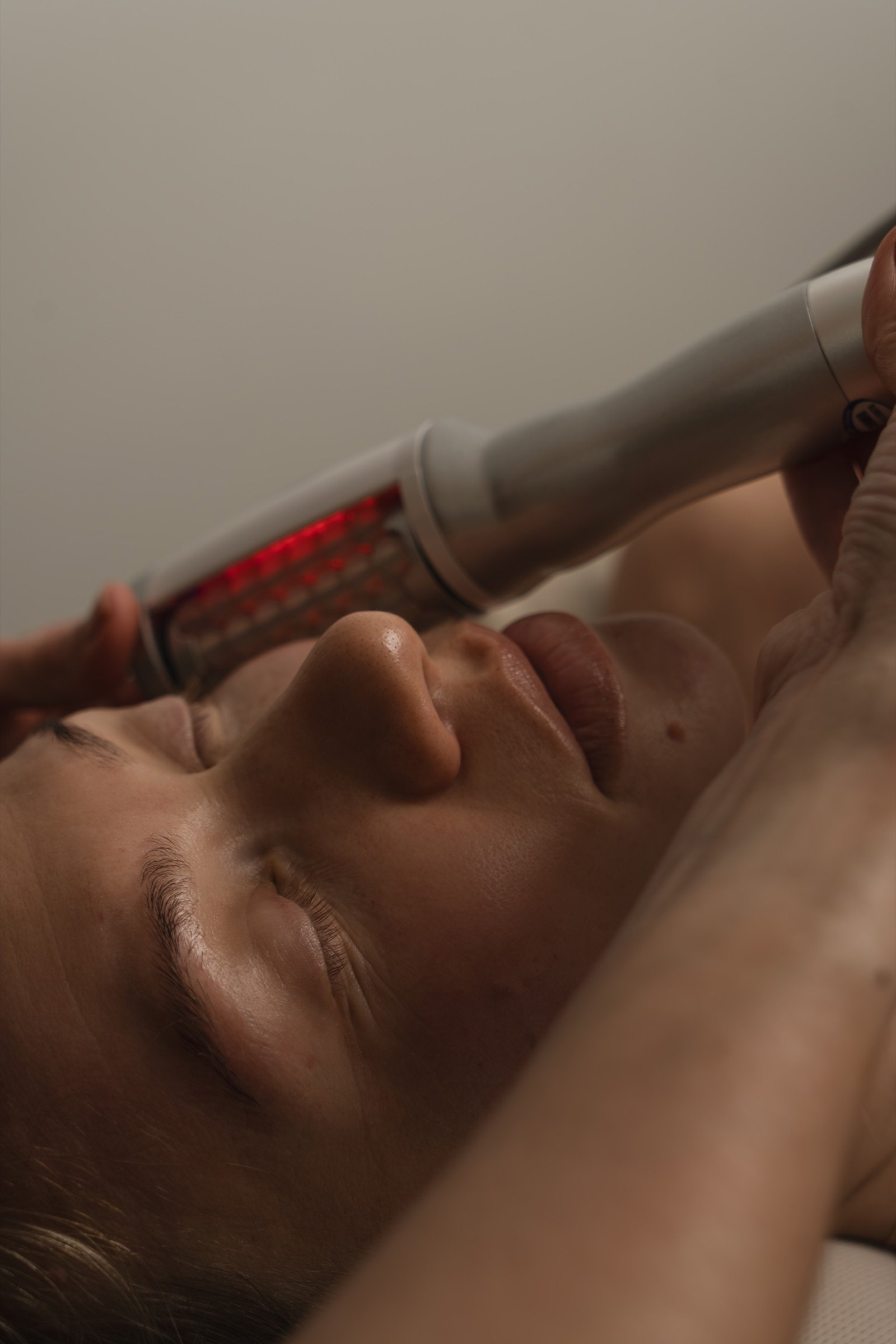 The face handpiece guided along the cheek and jawline during a face contouring session